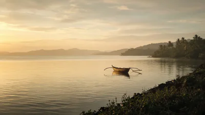 A small outrigger boat resting on a golden evening bay