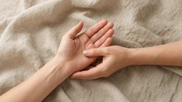 A thumb pressing gently into the centre of the other palm